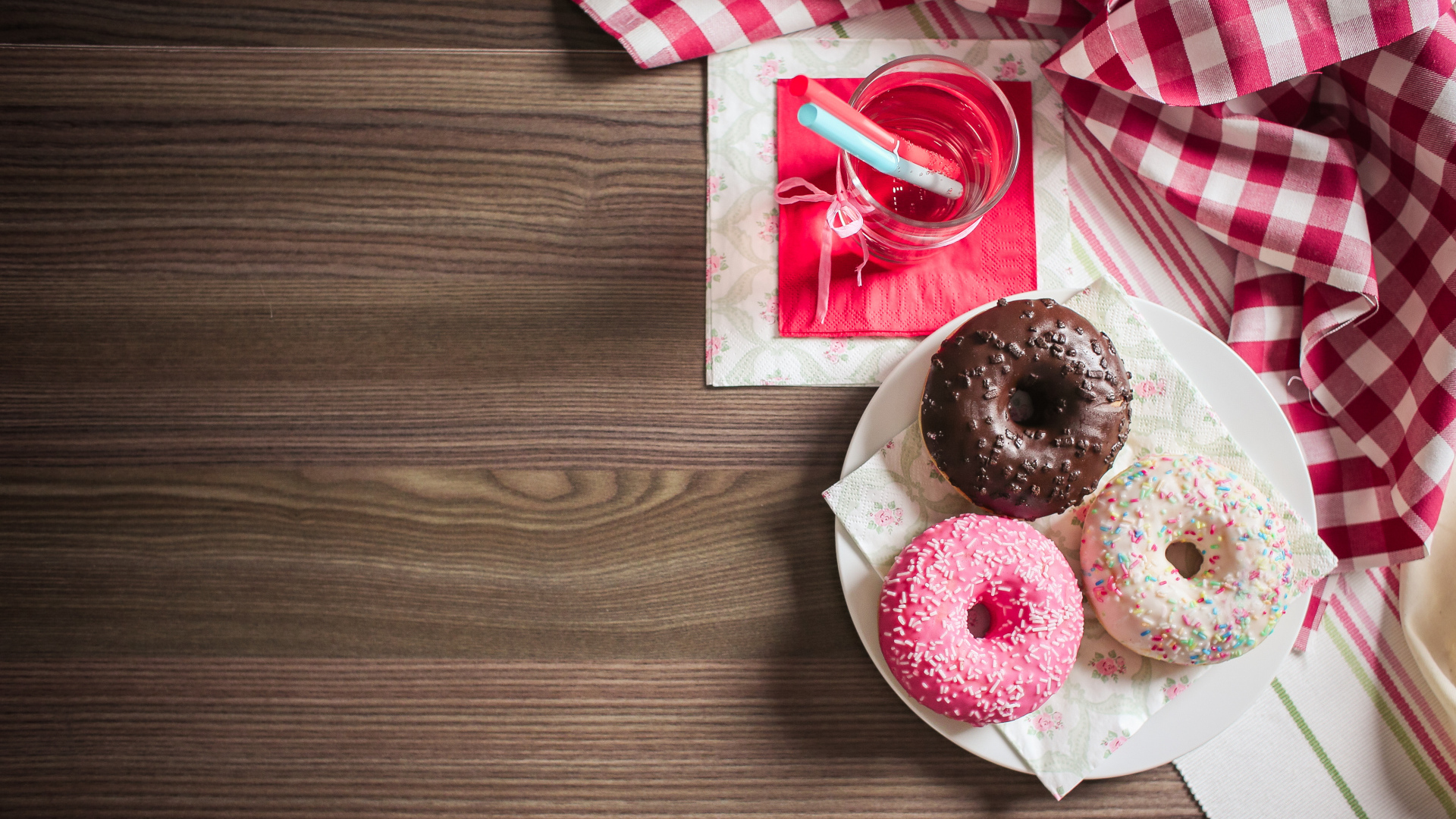 Три сладких пончика с глазурью на столе с лимонадом