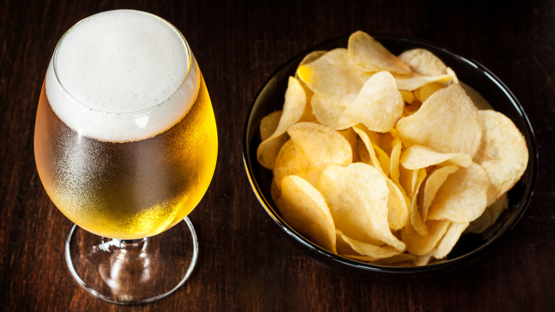 Миска с чипсами на столе с бокалом пива 