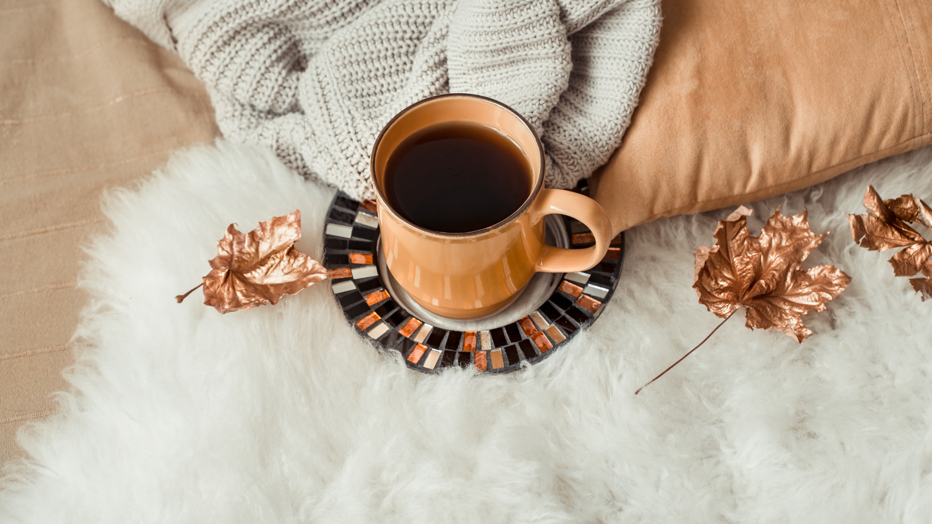 Чашка кофе стоит на покрывале с теплым свитером 