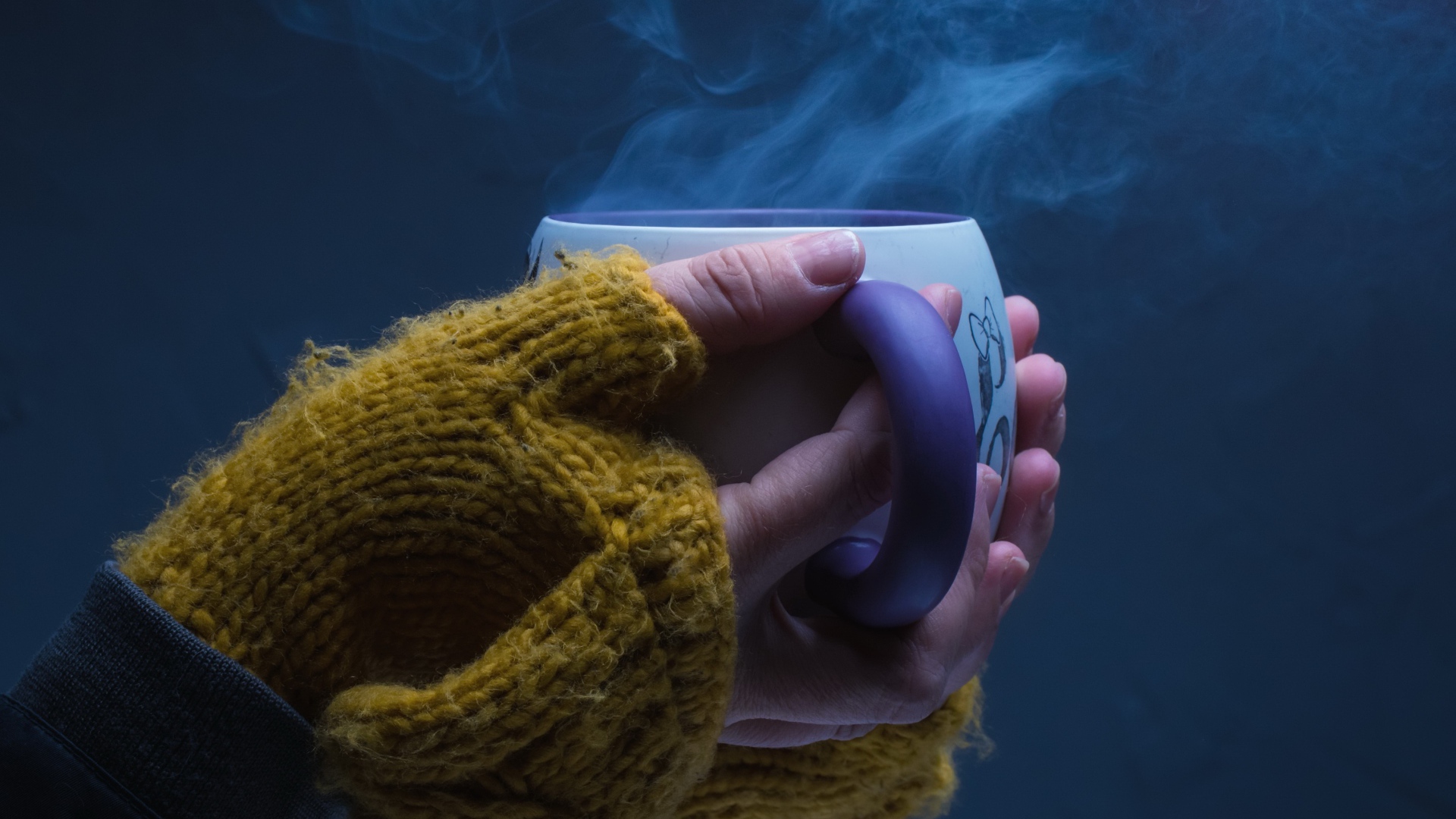 Чашка горячего кофе в руках у девушки на сером фоне