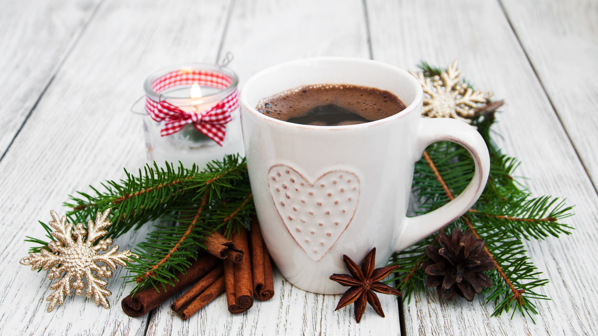 Чашка кофе на столе с еловой веткой, корицей и свечой