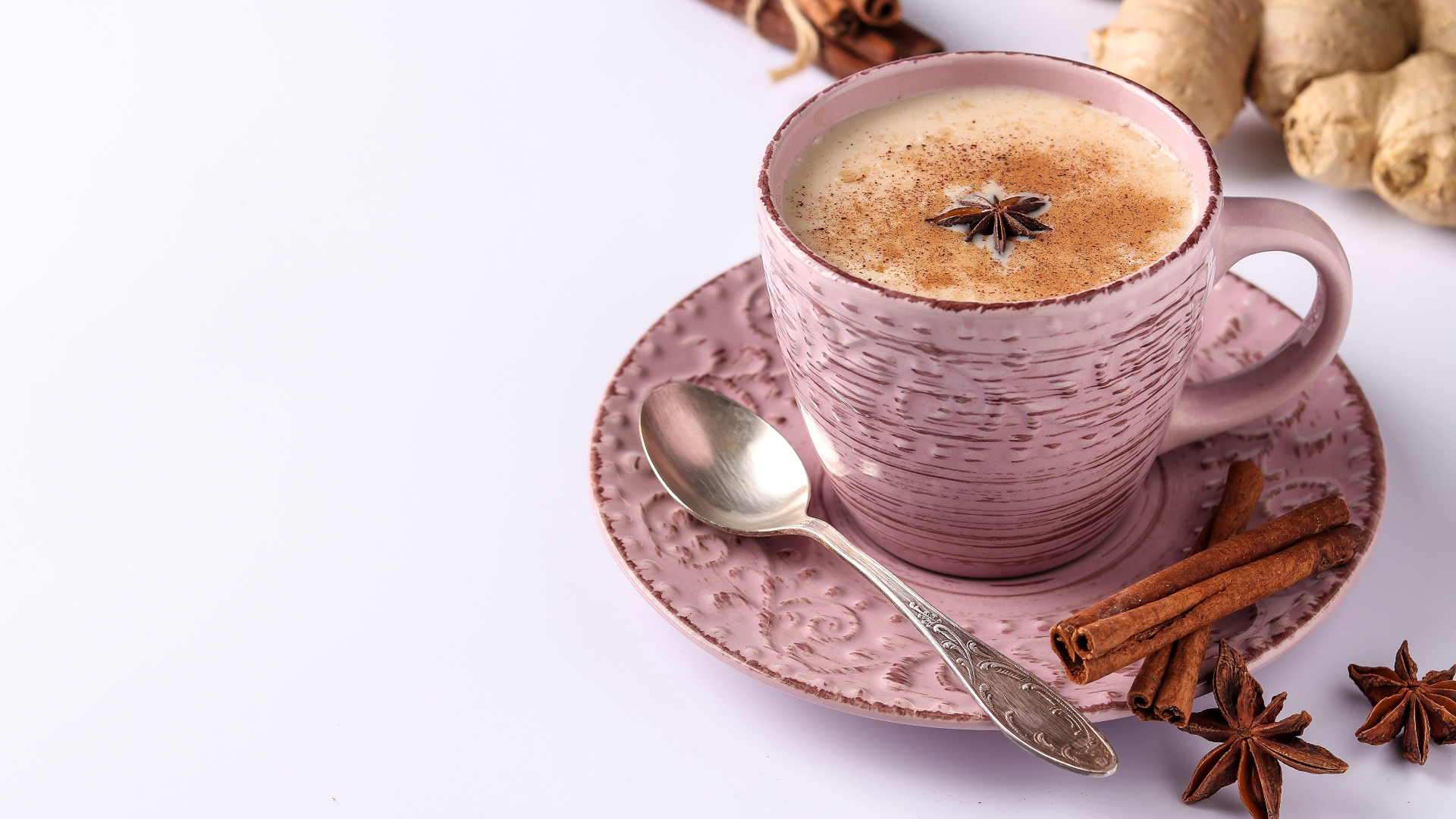 Чашка кофе на столе с корицей, бадьяном и  имбирем на белом фоне 