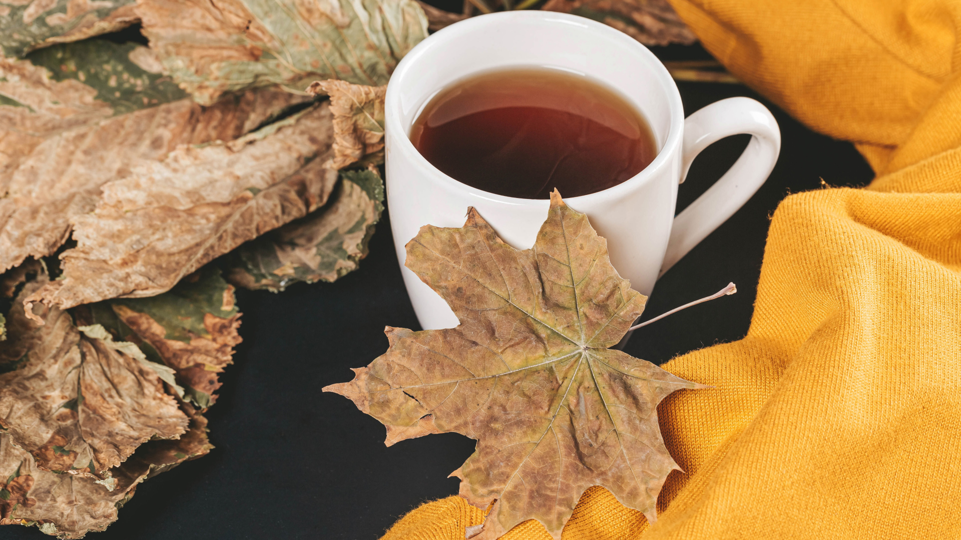 Чашка горячего чая на столе с сухими листьями
