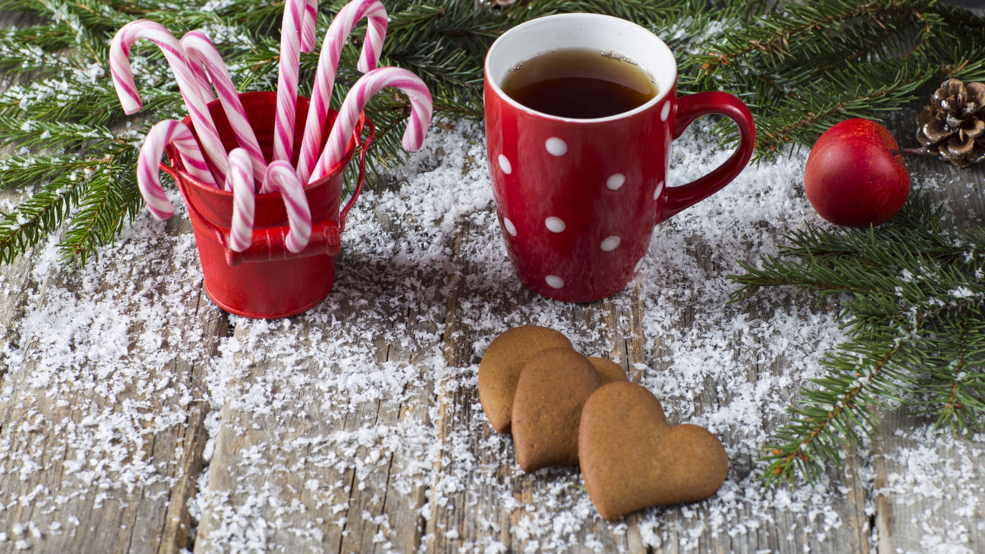 Чашка чая на столе с конфетами, печеньем и еловыми ветками