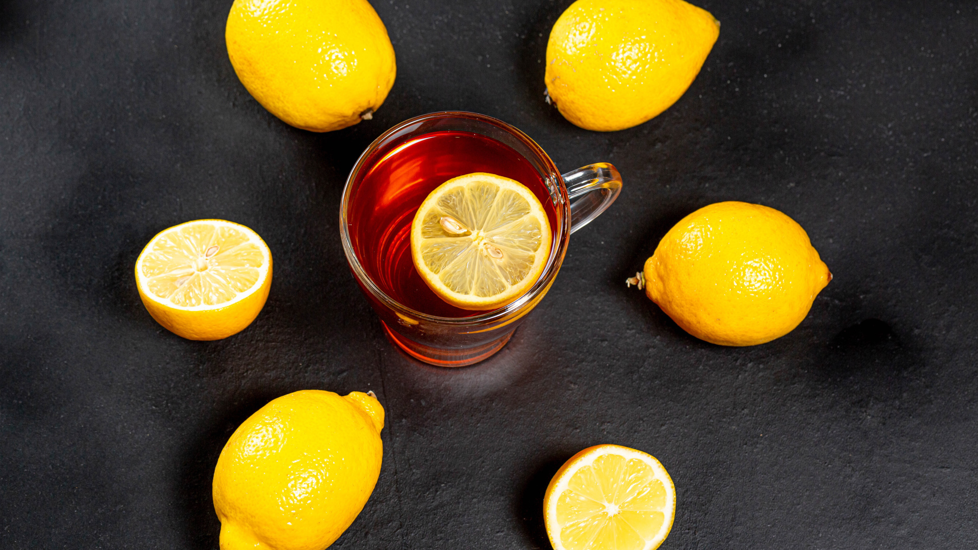 Стеклянная чашка чая с лимоном на сером столе 