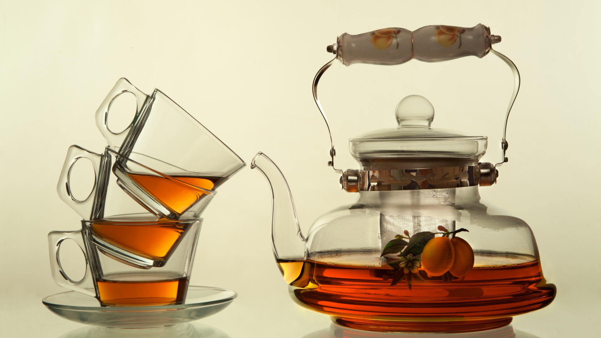 Стеклянный чайник с чашками на белом фоне