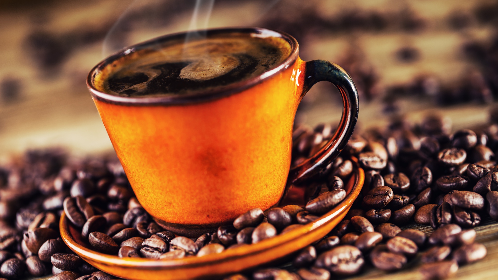 Оранжевая чашка горячего ароматного кофе на столе с зернами