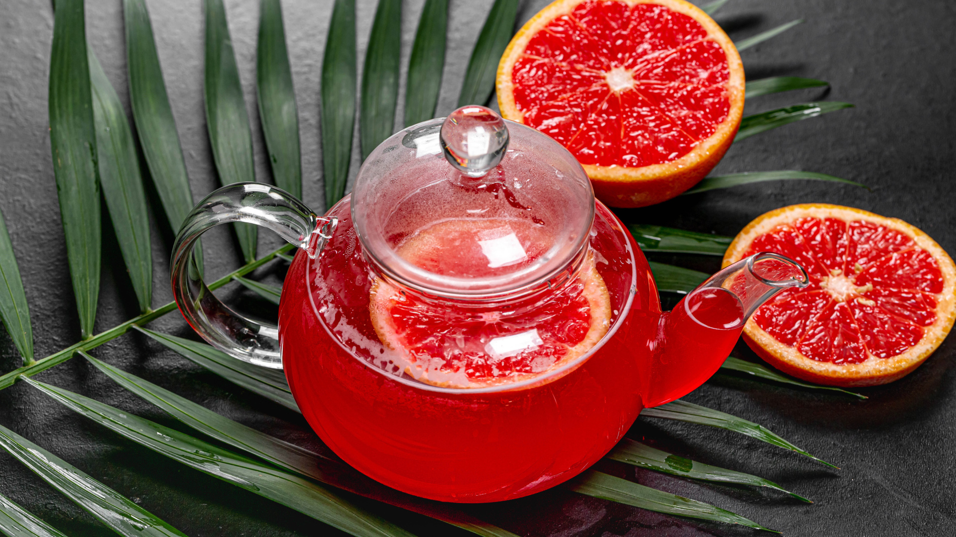 Красный чай в чайнике на столе в грейпфрутом и листьями