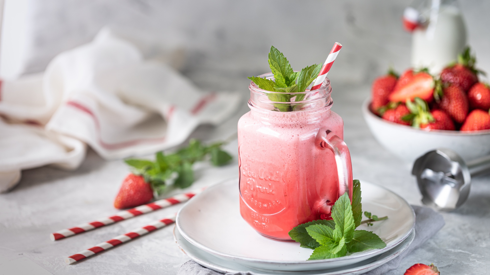 Смузи с клубникой в банке с трубочкой и листьями мяты