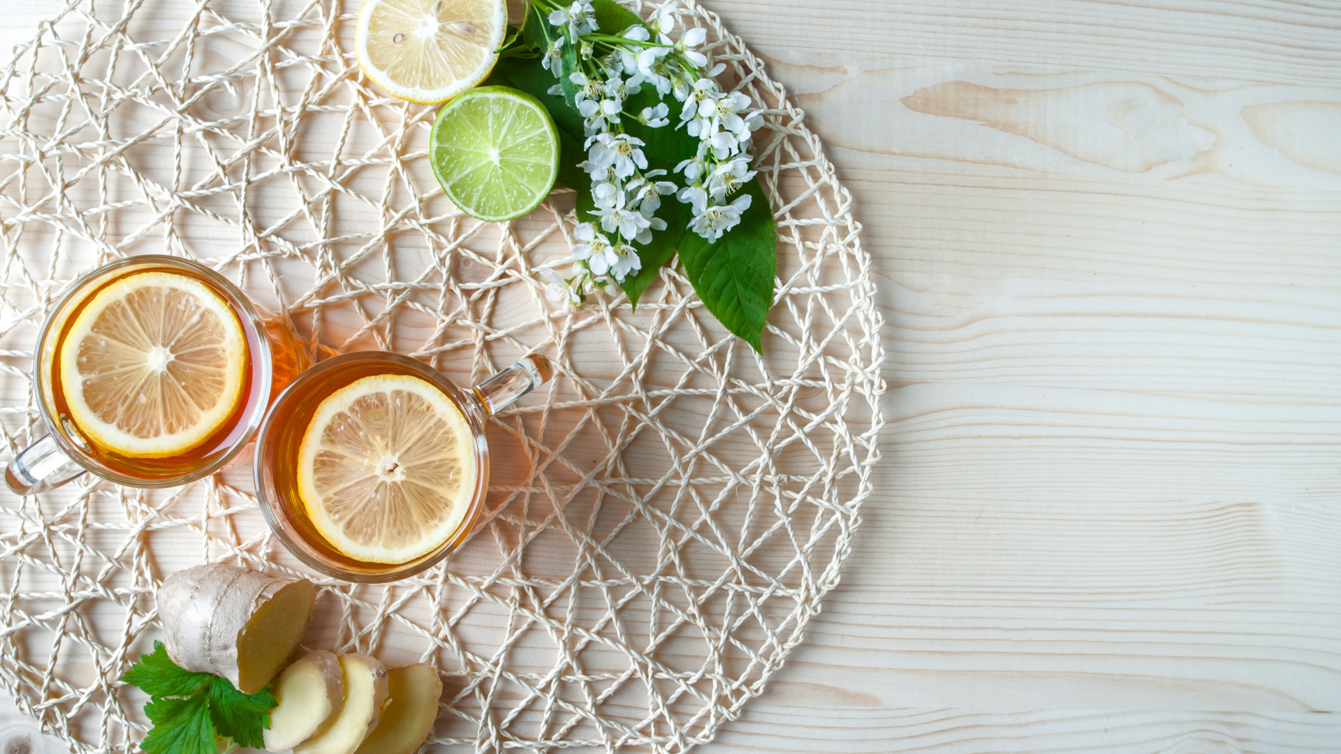 Две чашки чая с лимоном на плетеной подставке 