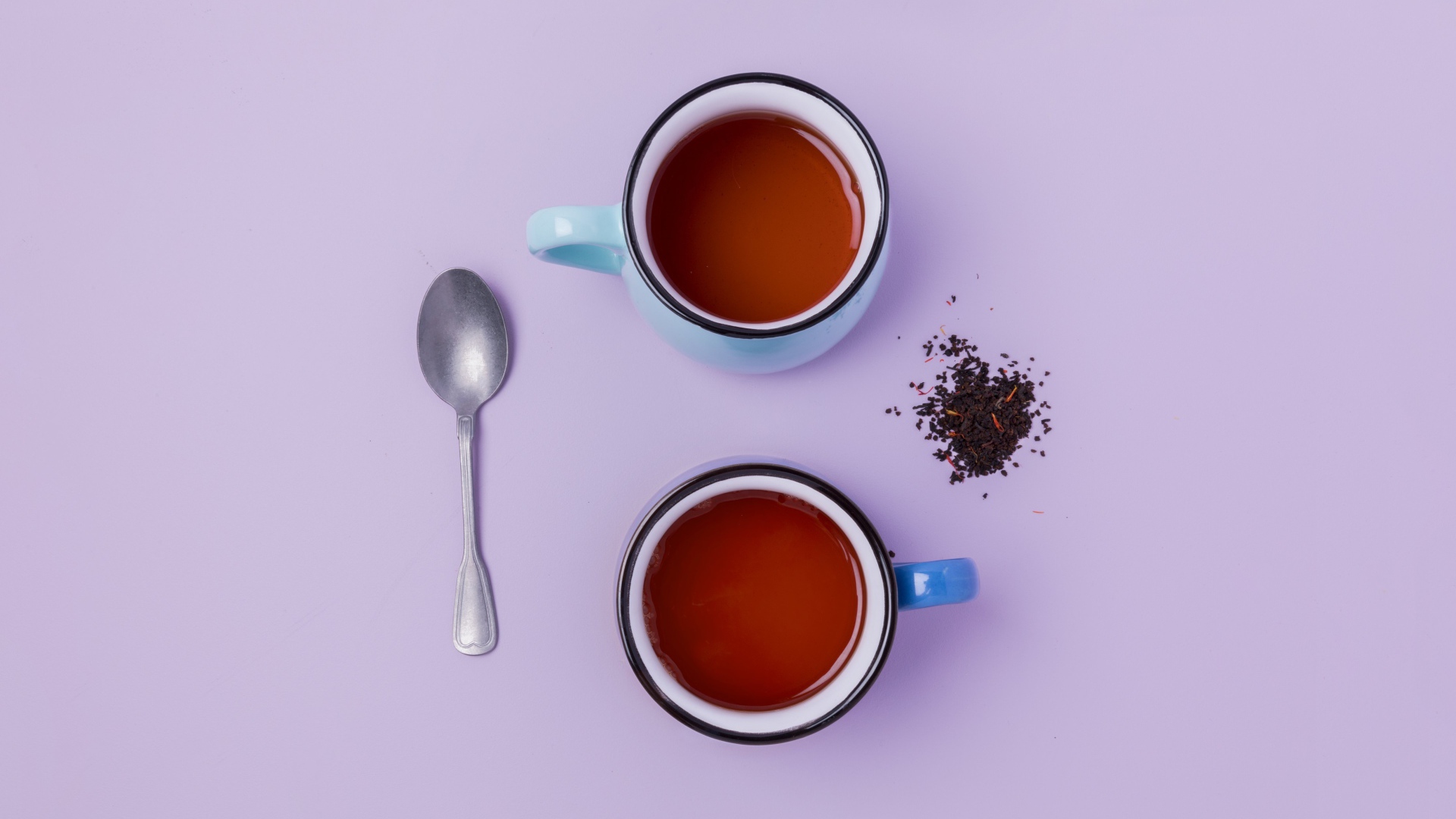 Две железные чашки чая на сиреневом фоне с ложкой