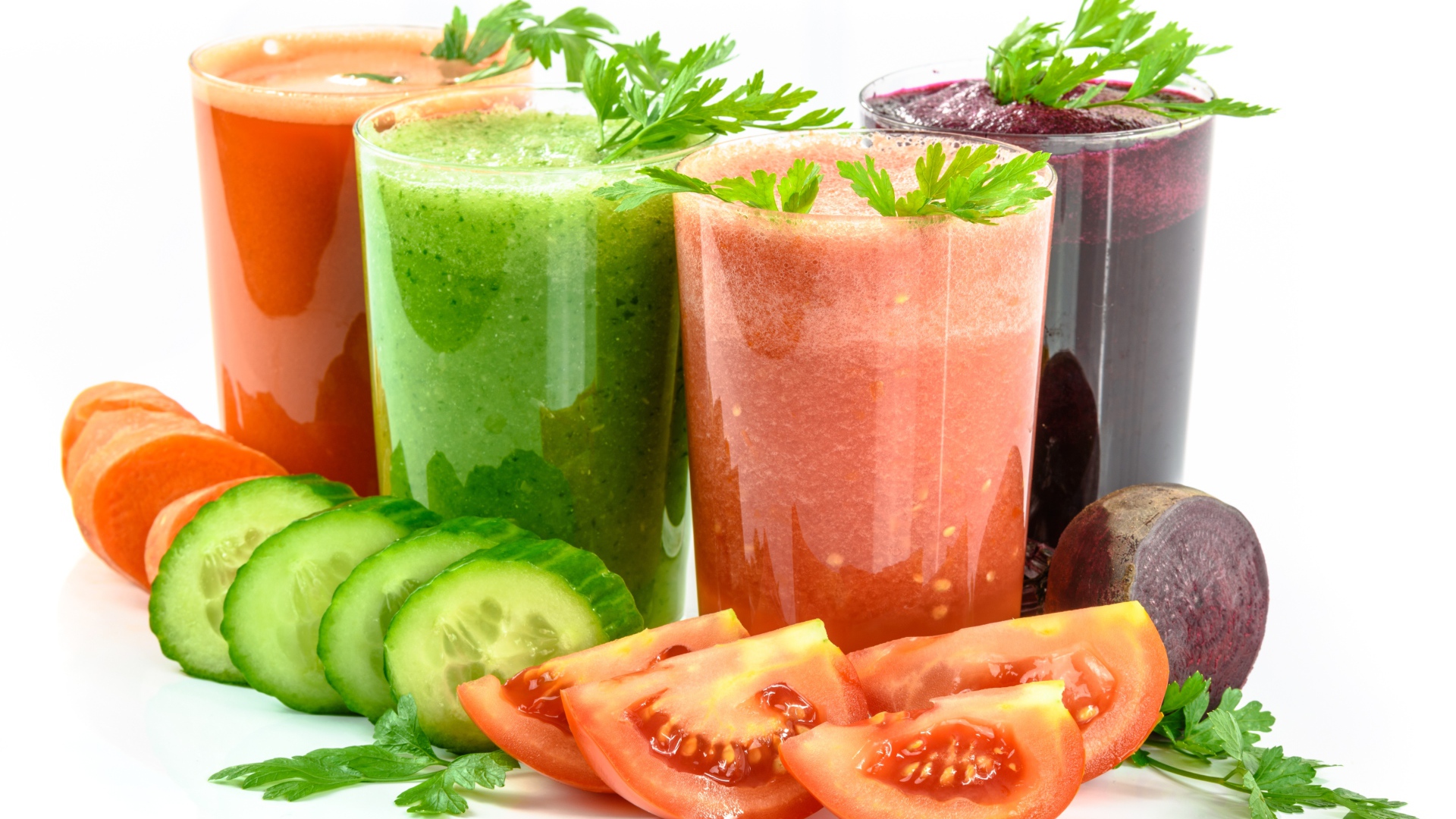 Овощные соки на столе с огурцами, помидорами, морковью и свеклой 
