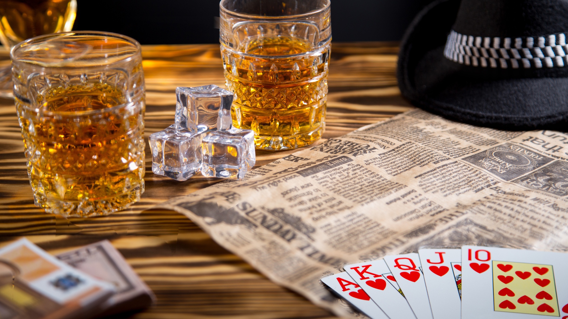 Виски со льдом на столе с картами, газетой и шляпой