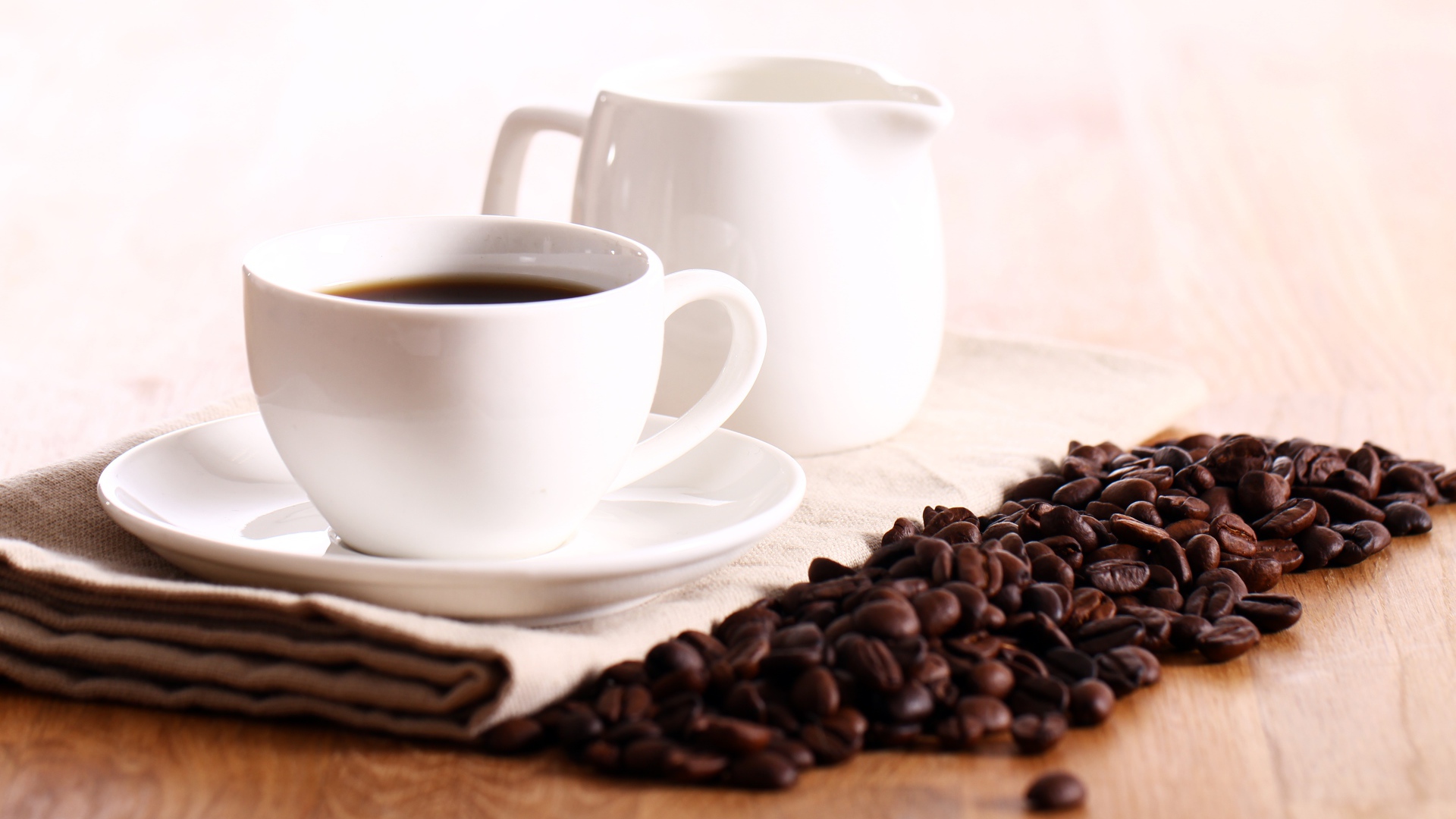 Белая чашка кофе на столе с молоком и зернами