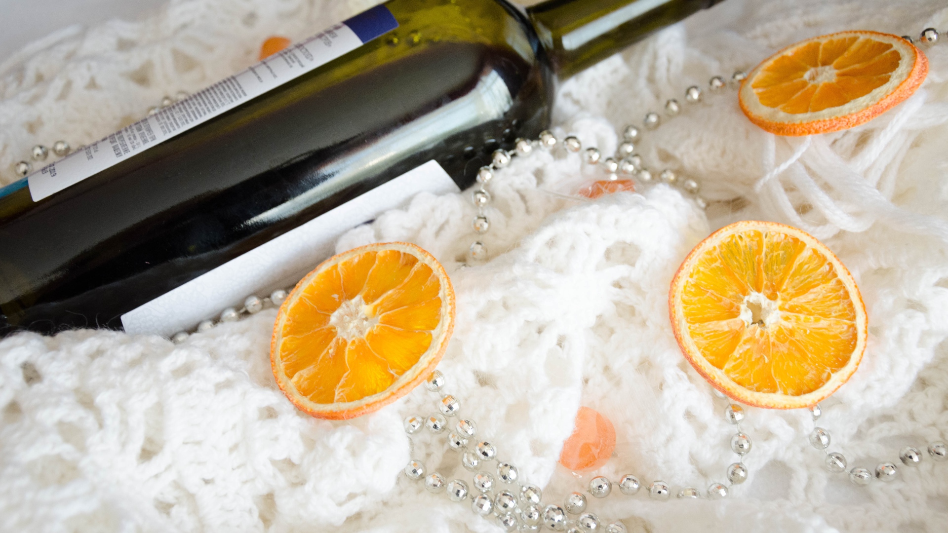 Бутылка вина и кусочки апельсина на белом платке 