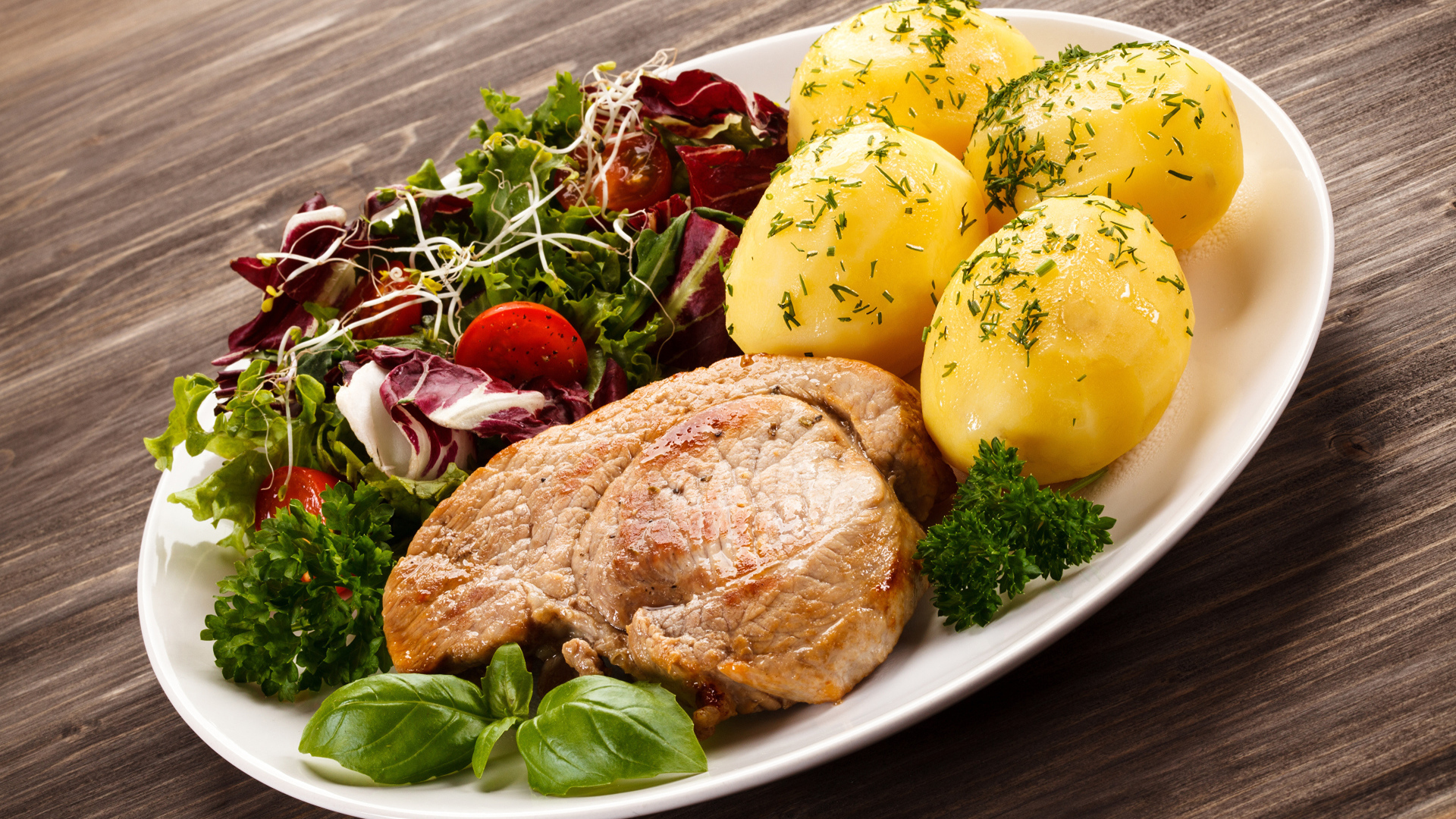 Кусок мяса на тарелке с картофелем и салатом