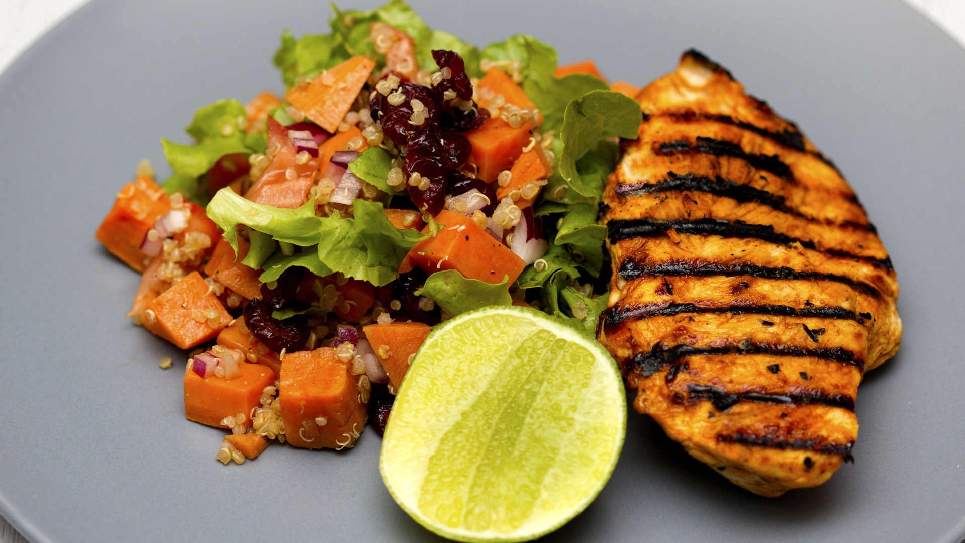 Запеченная куриная грудка с овощами и лаймом на тарелке 