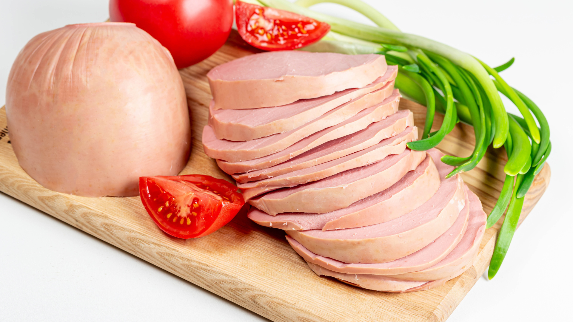 Вареная колбаса на доске с луком и помидором