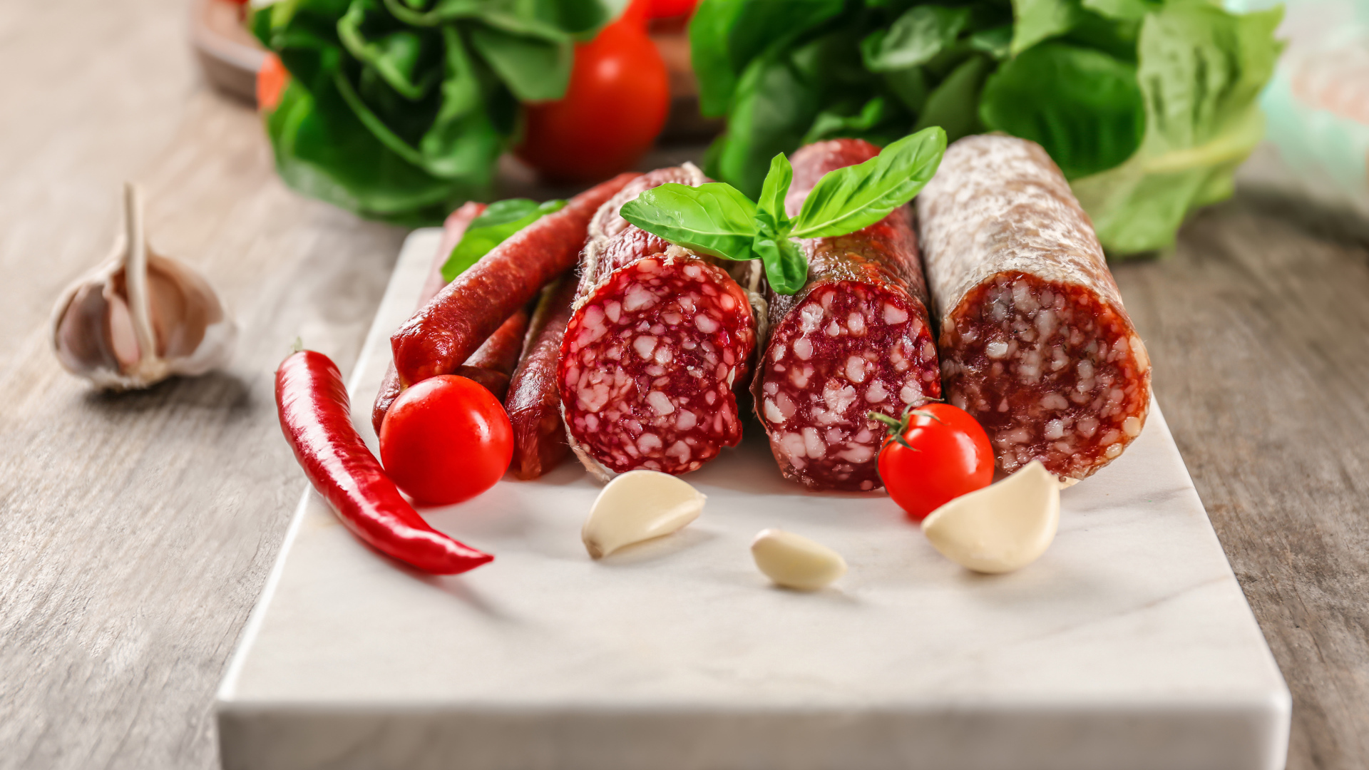 Вкусные колбасные изделия на столе с овощами