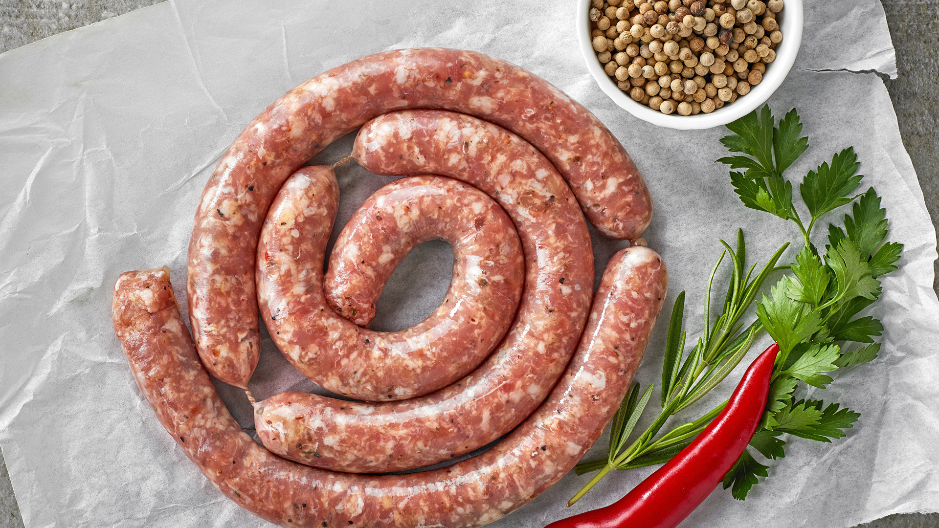 Домашняя колбаса на столе с зеленью и перцем