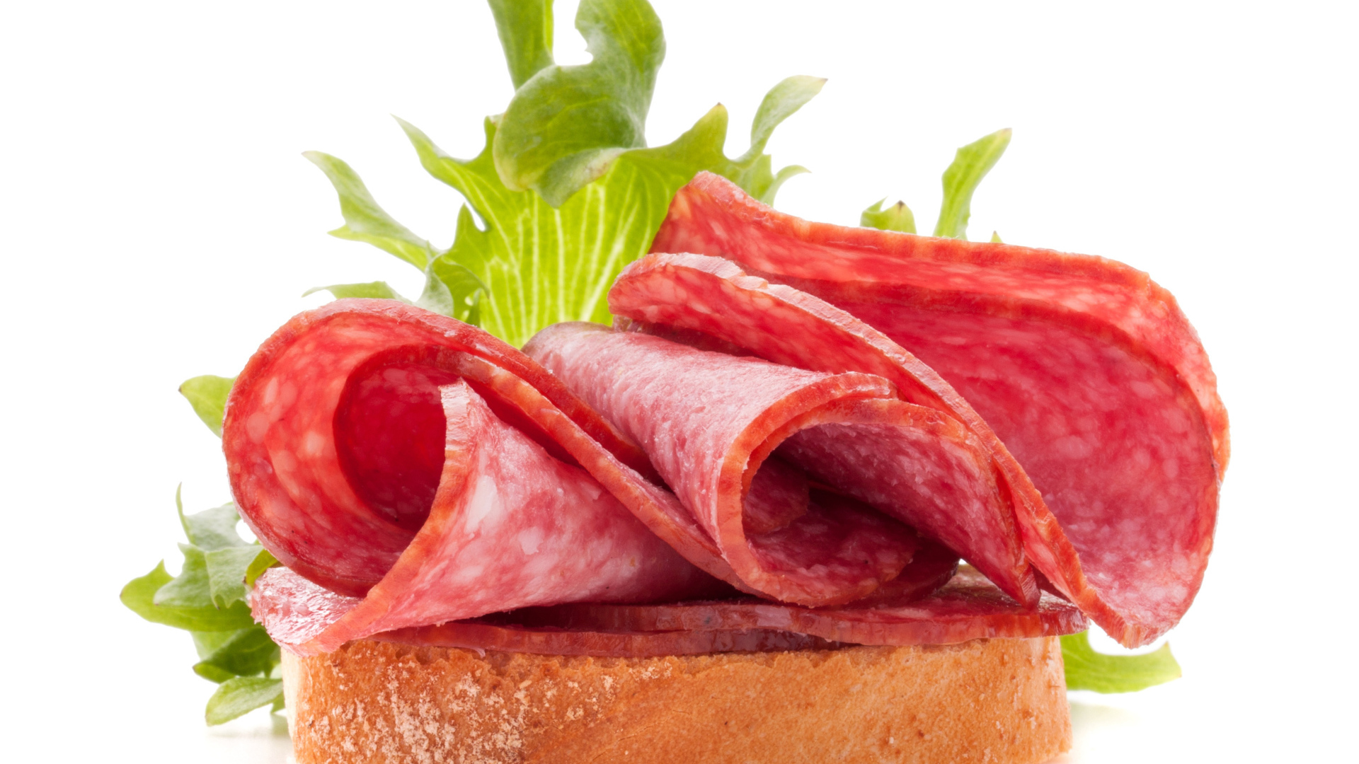 Бутерброд с листьями салата и колбасой на белом фоне