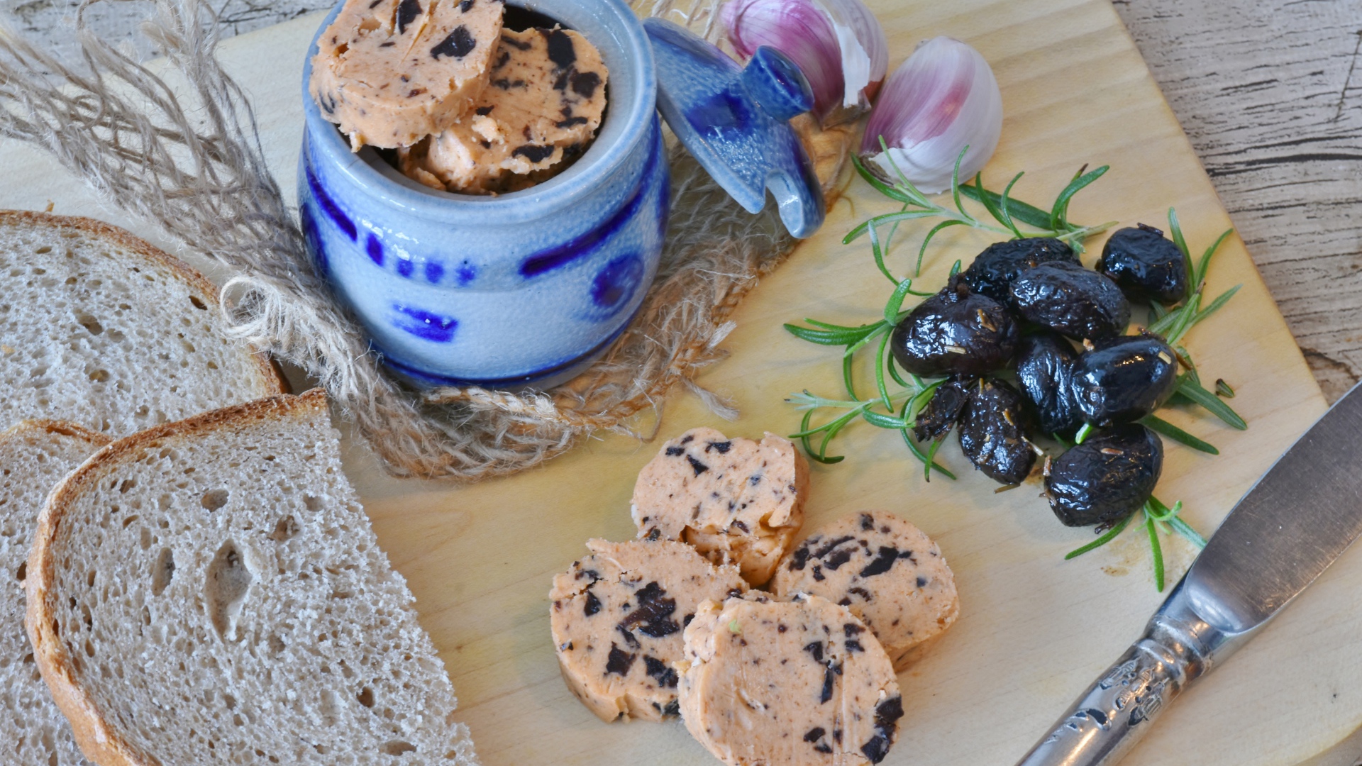 Колбаса с маслинами на столе с хлебом и чесноком