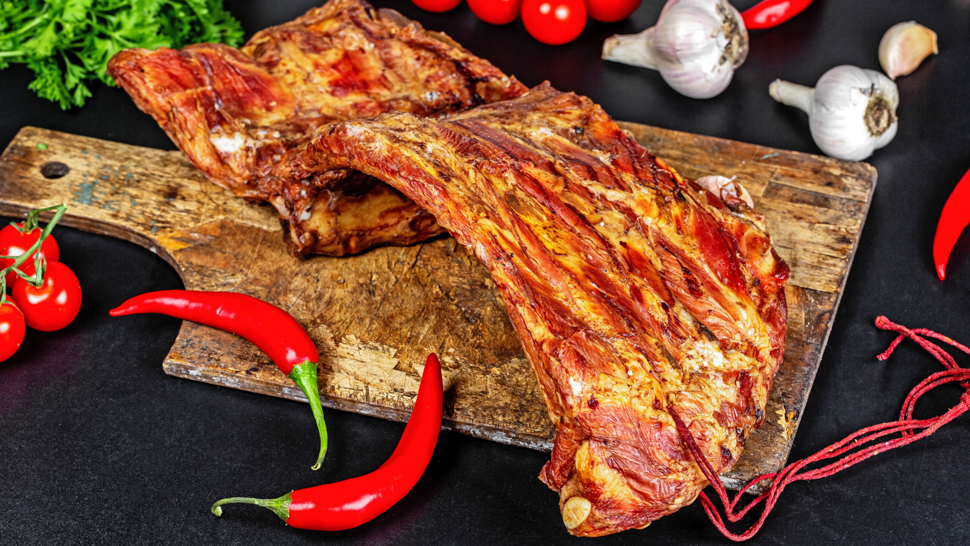Копченые ребра на столе с красным перцем, чесноком и помидорами