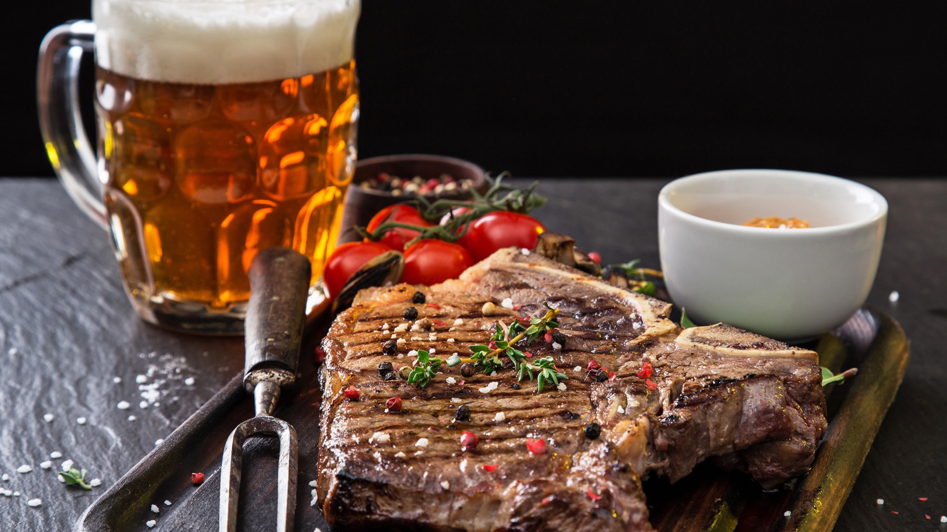 Вкусный кусок мяса на столе с помидорами и бокалом пива