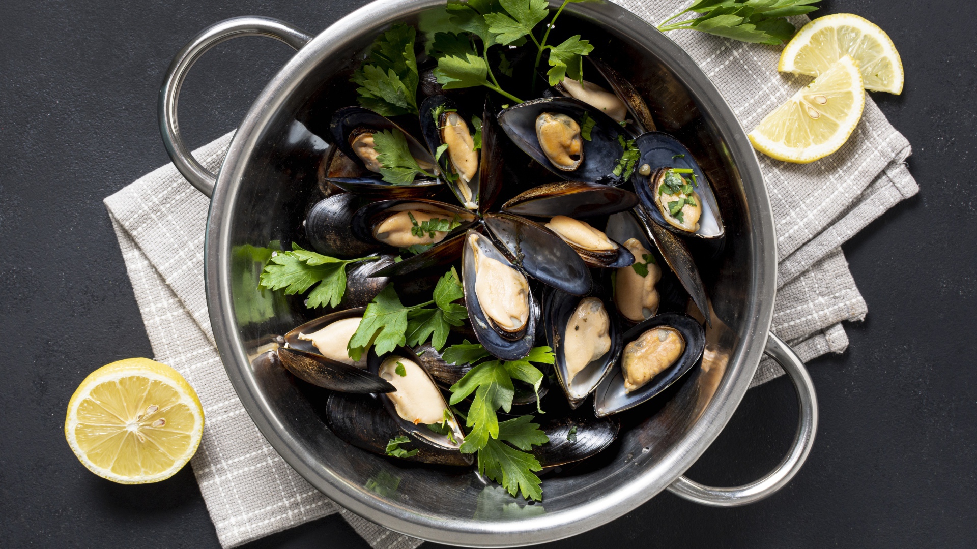 Свежие мидии в кастрюле с зеленью петрушки 