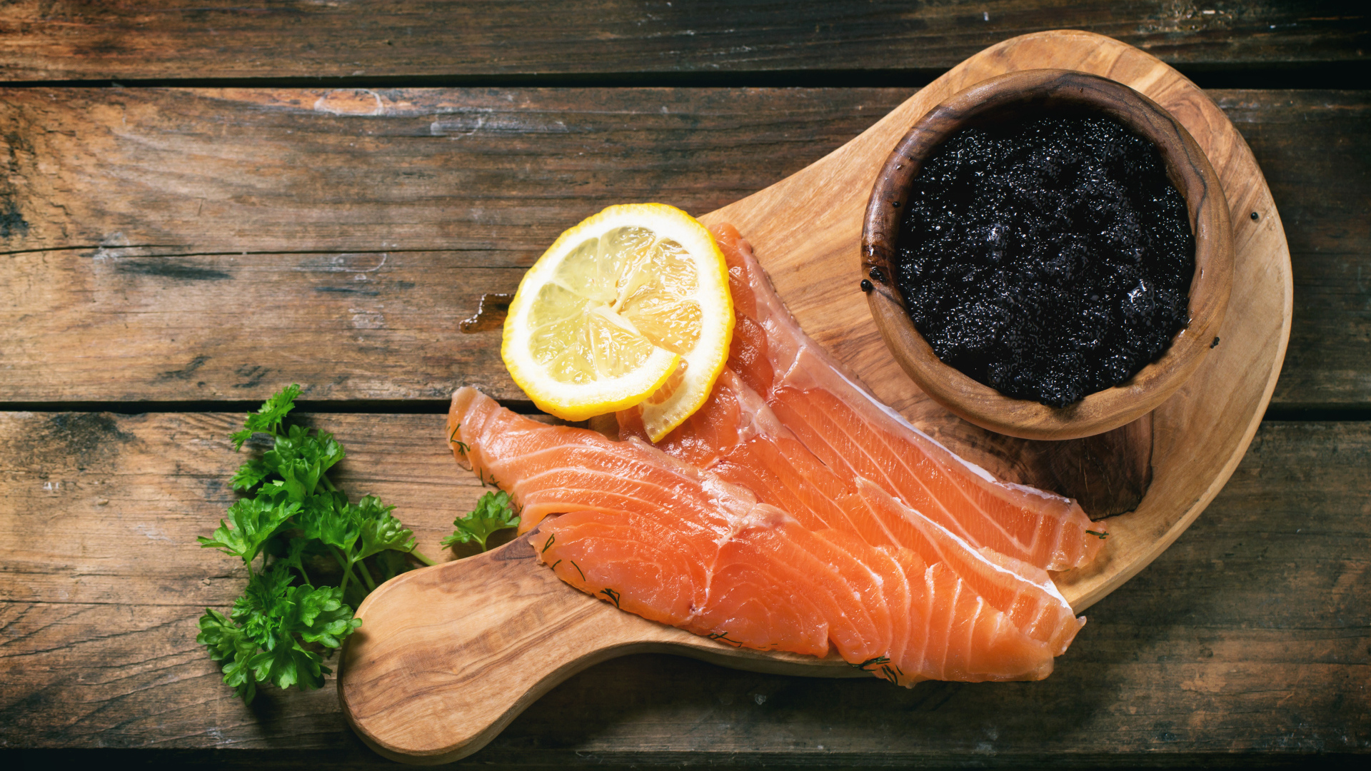 Кусочки красной рыбы с лимоном на столе с черной икрой 