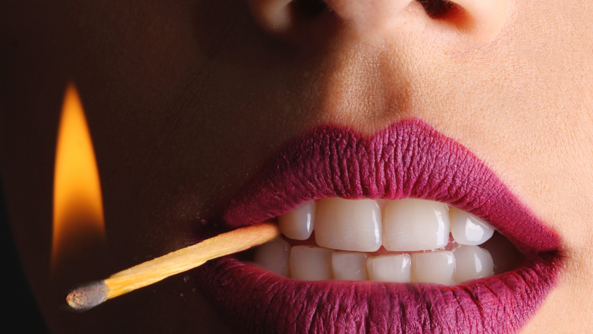 Зажженная спичка в зубах у девушки 