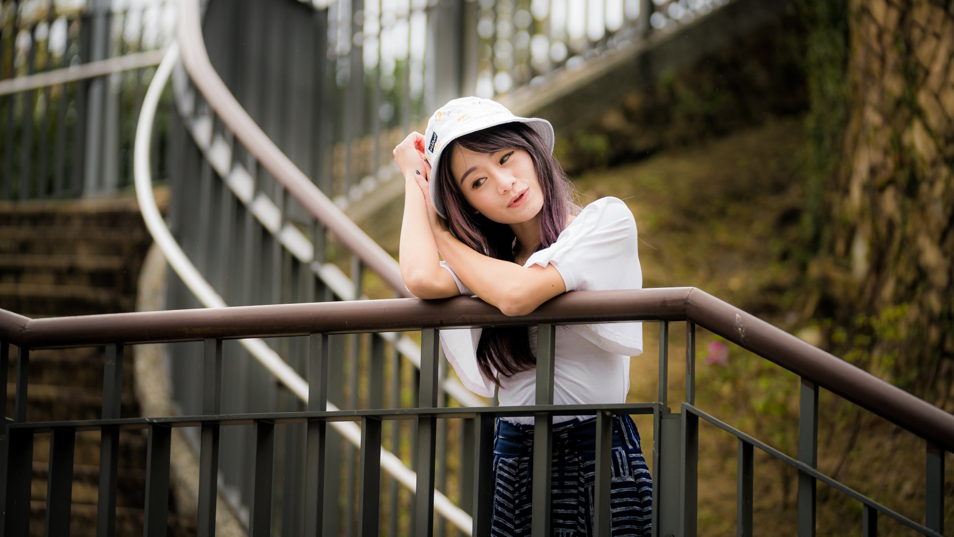 Молодая девушка азиатка стоит на лестнице у перил 