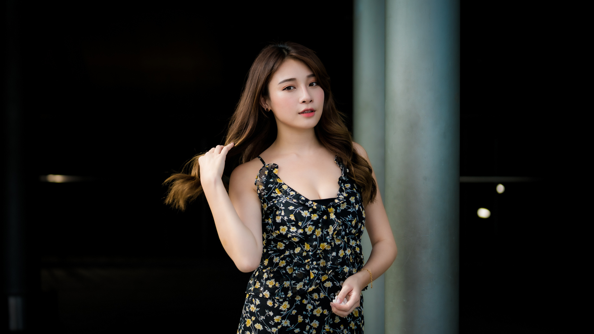 Девушка азиатка в платье трогает волосы 