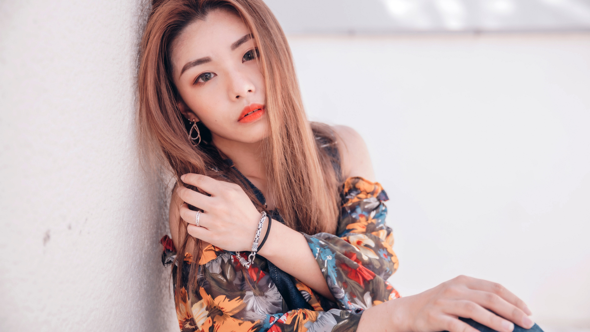 Девушка азиатка сидит на полу у стены 