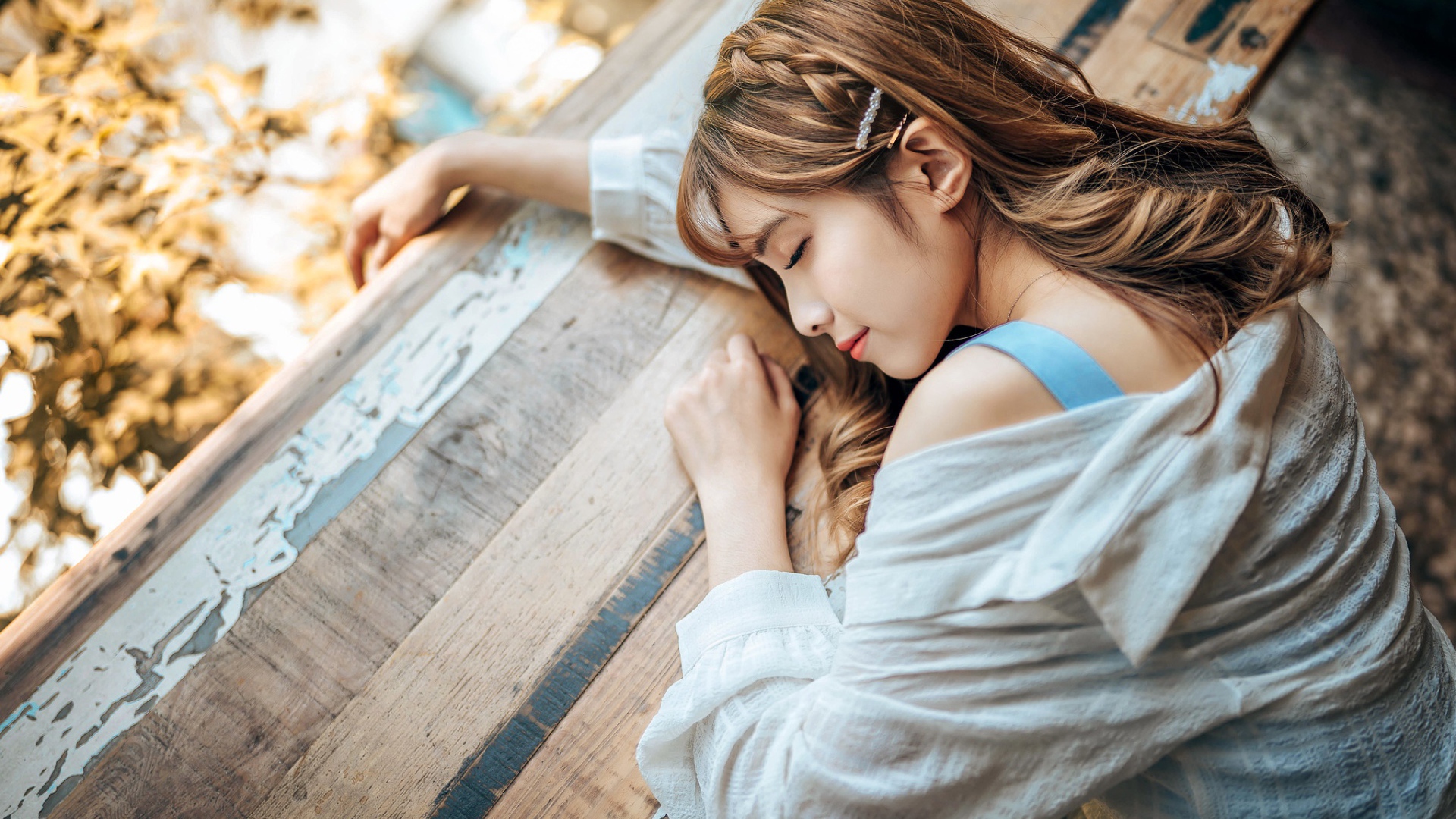 Девушка азиатка спит на деревянном столе 