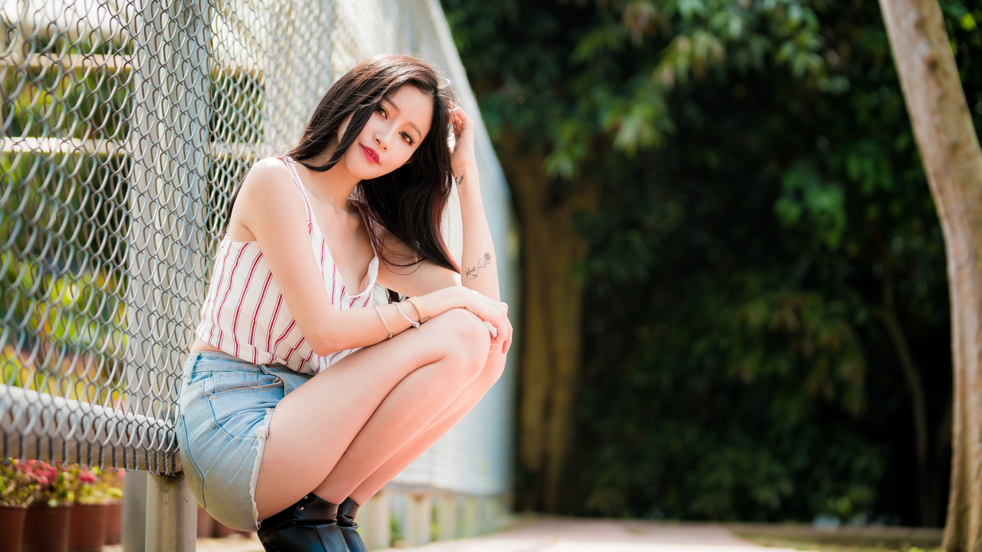 Красивая девушка азиатка сидит у железной сетки