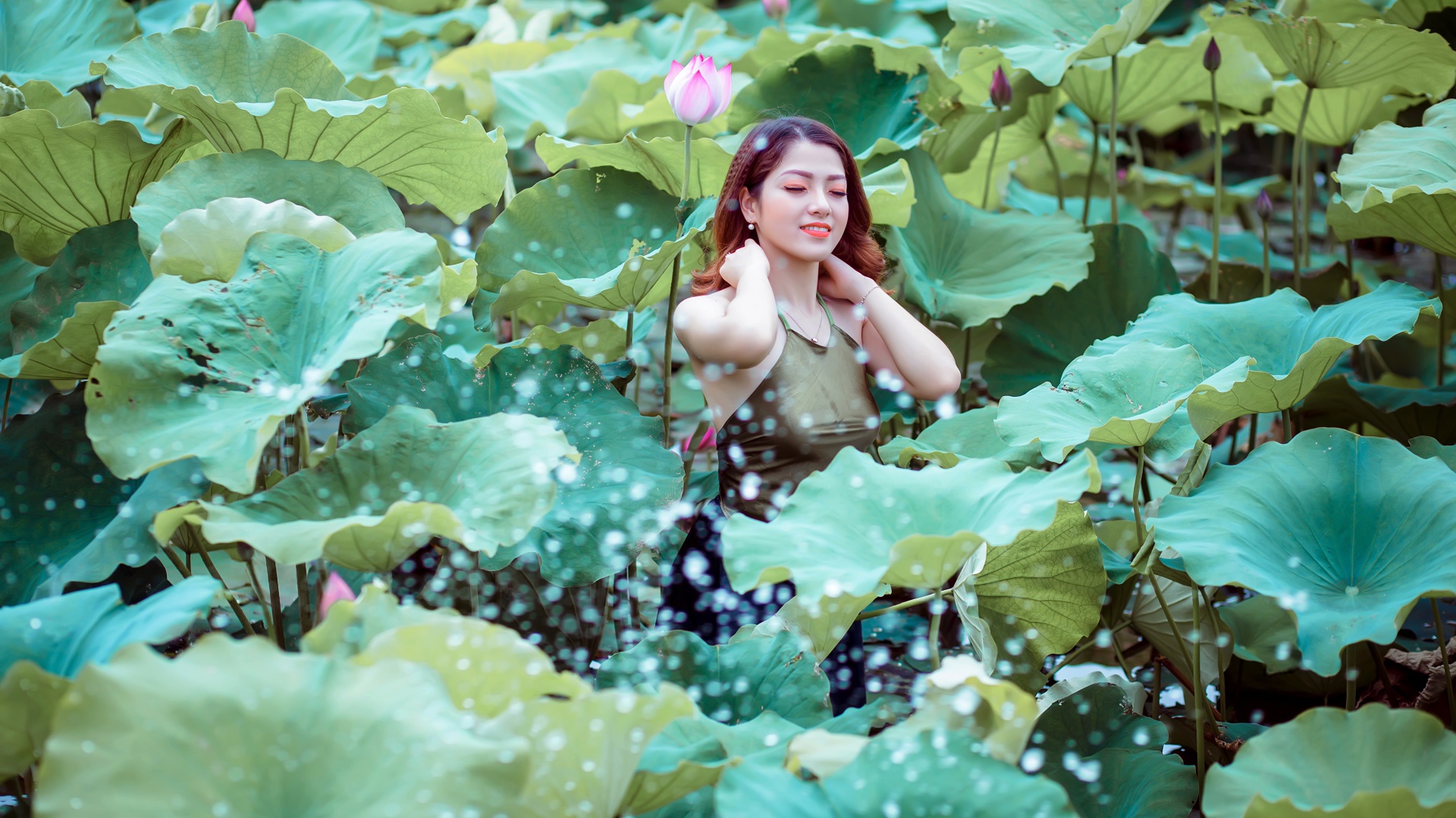 Красивая девушка азиатка в зеленых листьях лотоса 