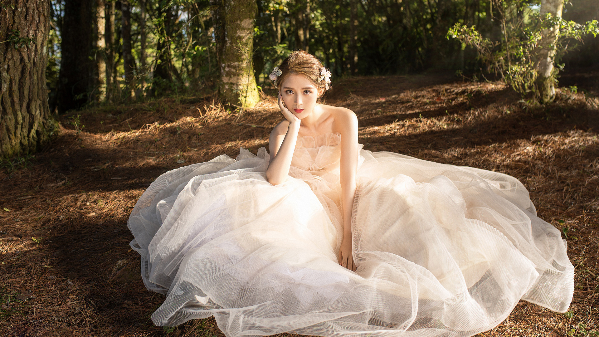 Красивая девушка азиатка в белом свадебном платье сидит на земле