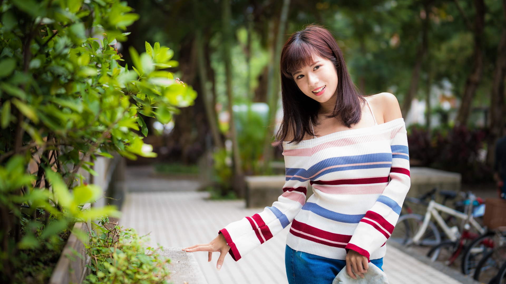 Красивая азиатка в полосатом свитере в парке