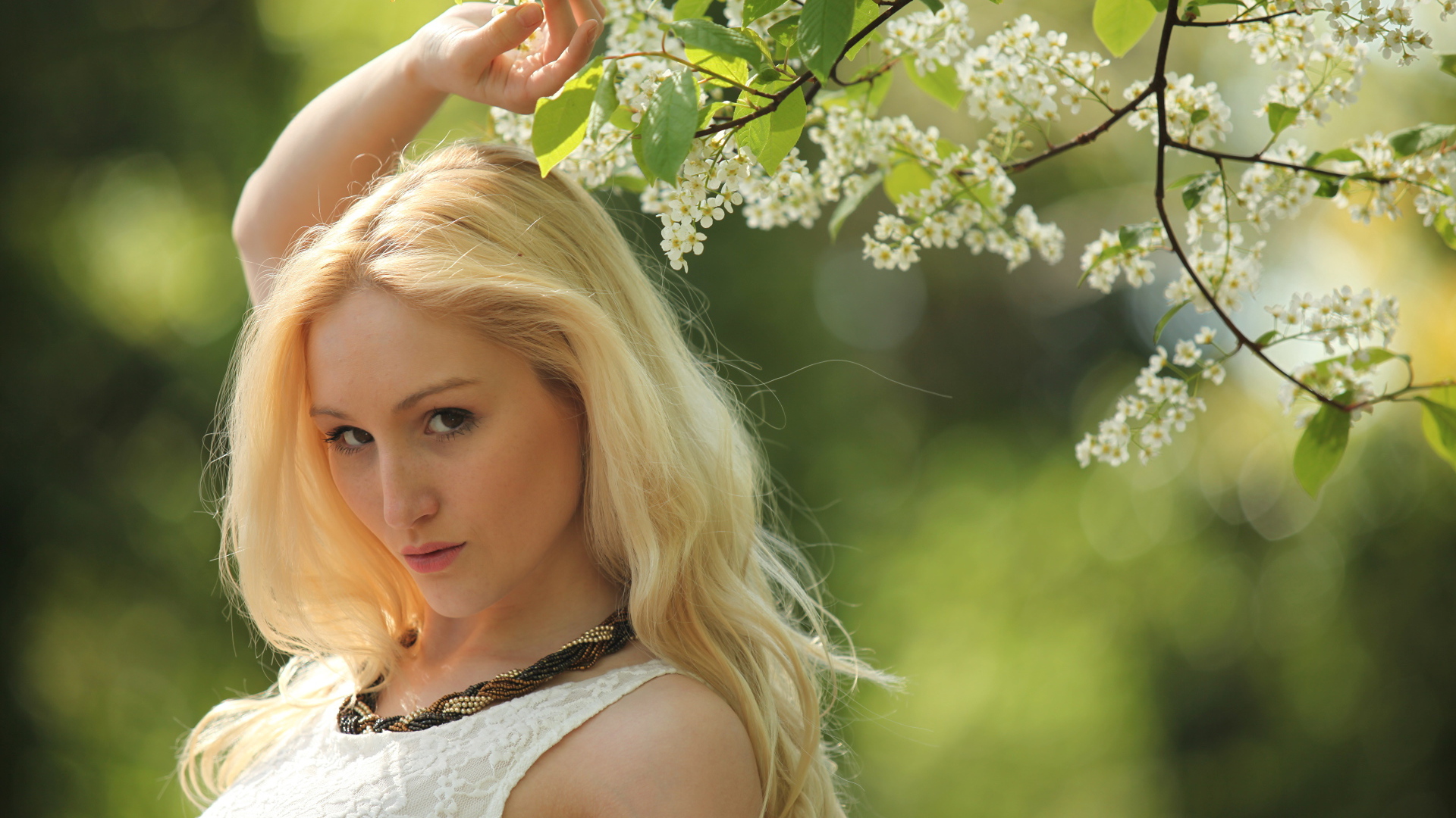 Красивая блондинка у ветки с белыми цветами