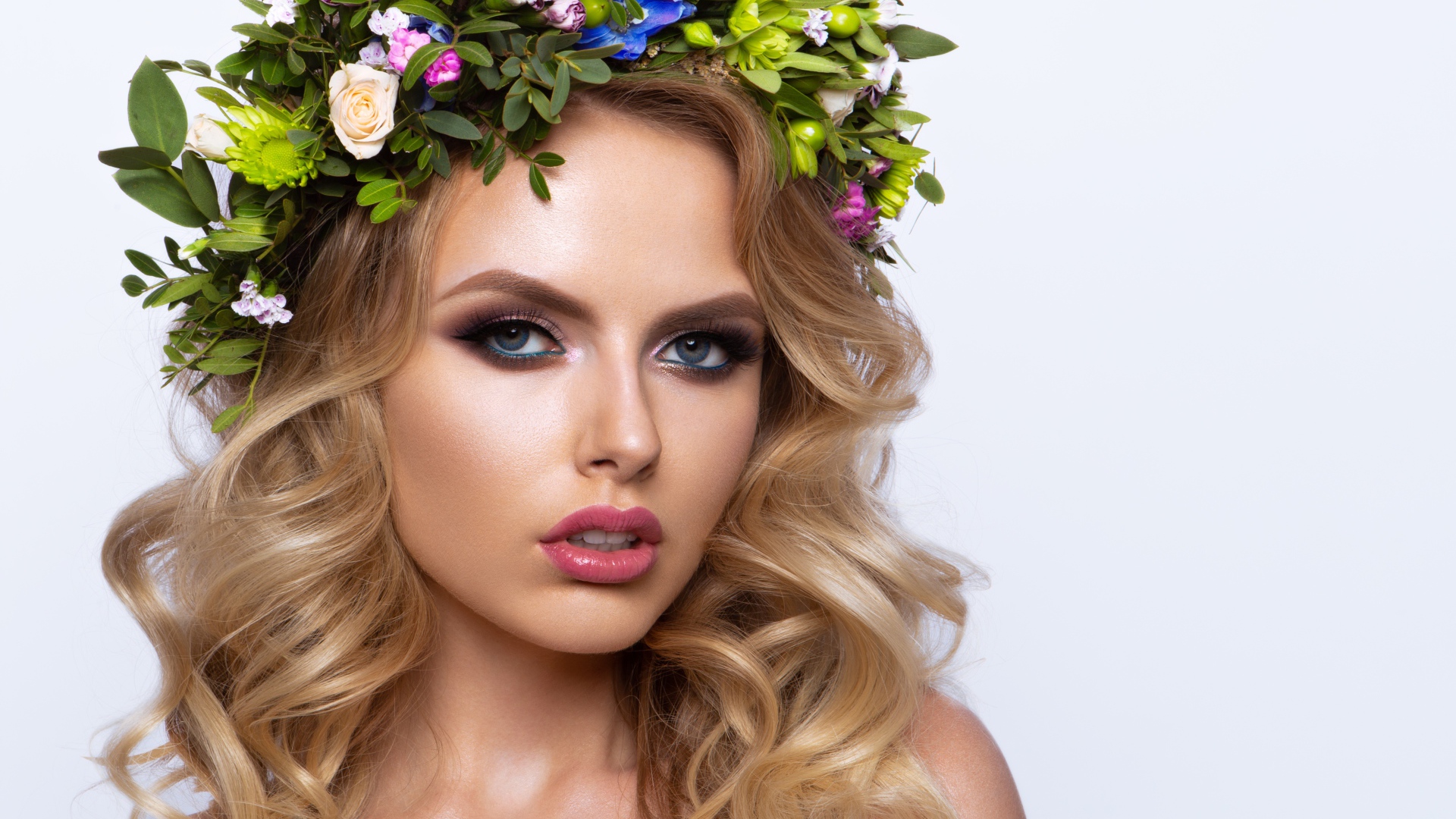 Красивая блондинка с венком из живых цветов на белом фоне