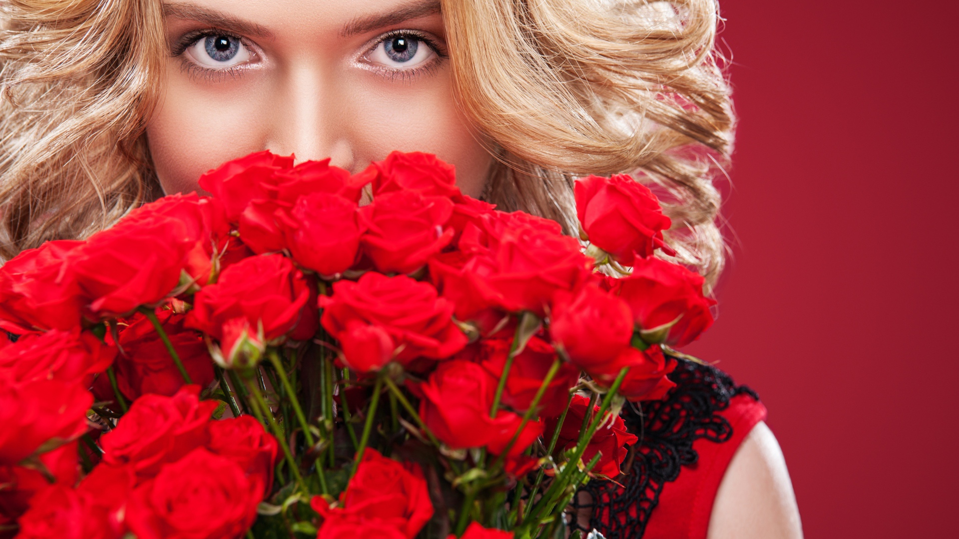 Красивая голубоглазая блондинка с букетом красных роз 
