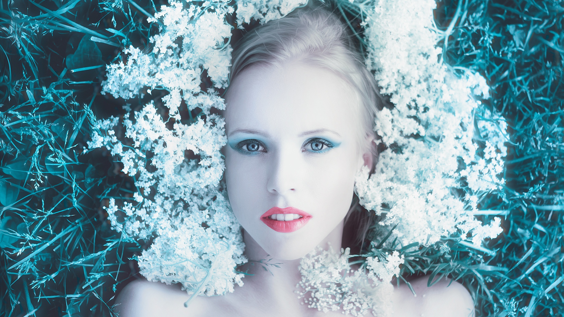 Красивая голубоглазая девушка на траве с белыми цветами