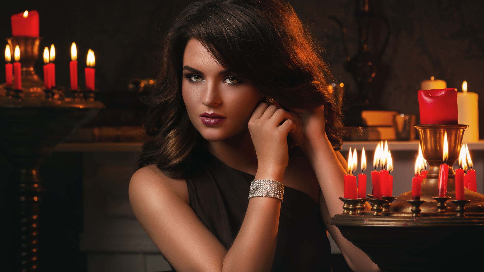 Красивая брюнетка в черном платье и зажженными свечами