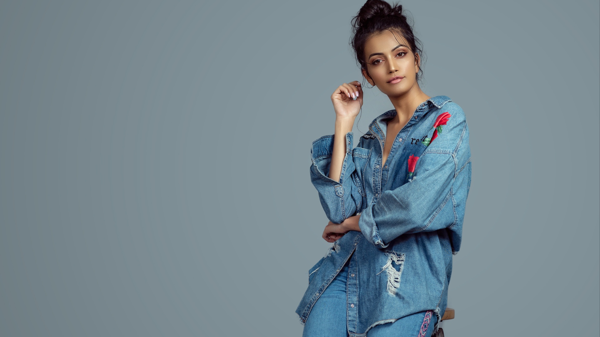 Красивая девушка в джинсовом костюме на сером фоне