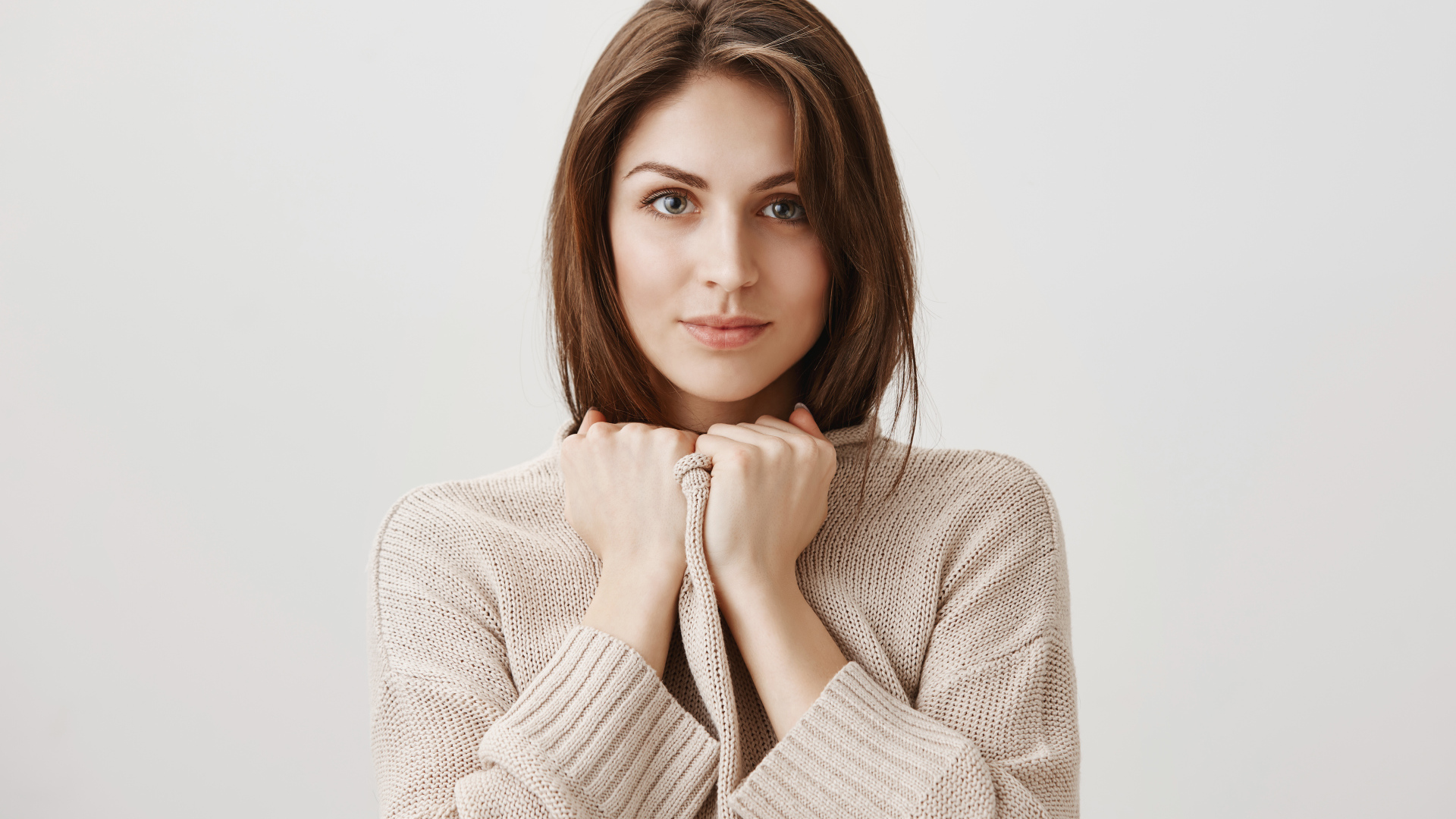 Красивая девушка в теплом свитере на сером фоне 