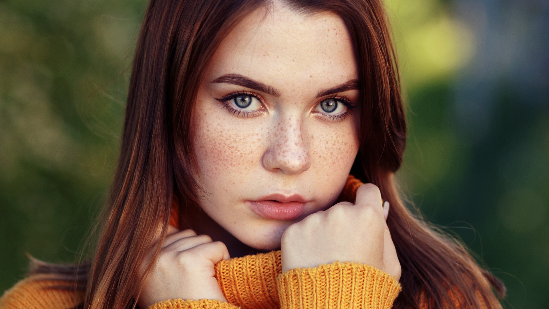 Красивая девушка в теплом свитере с веснушками на лице