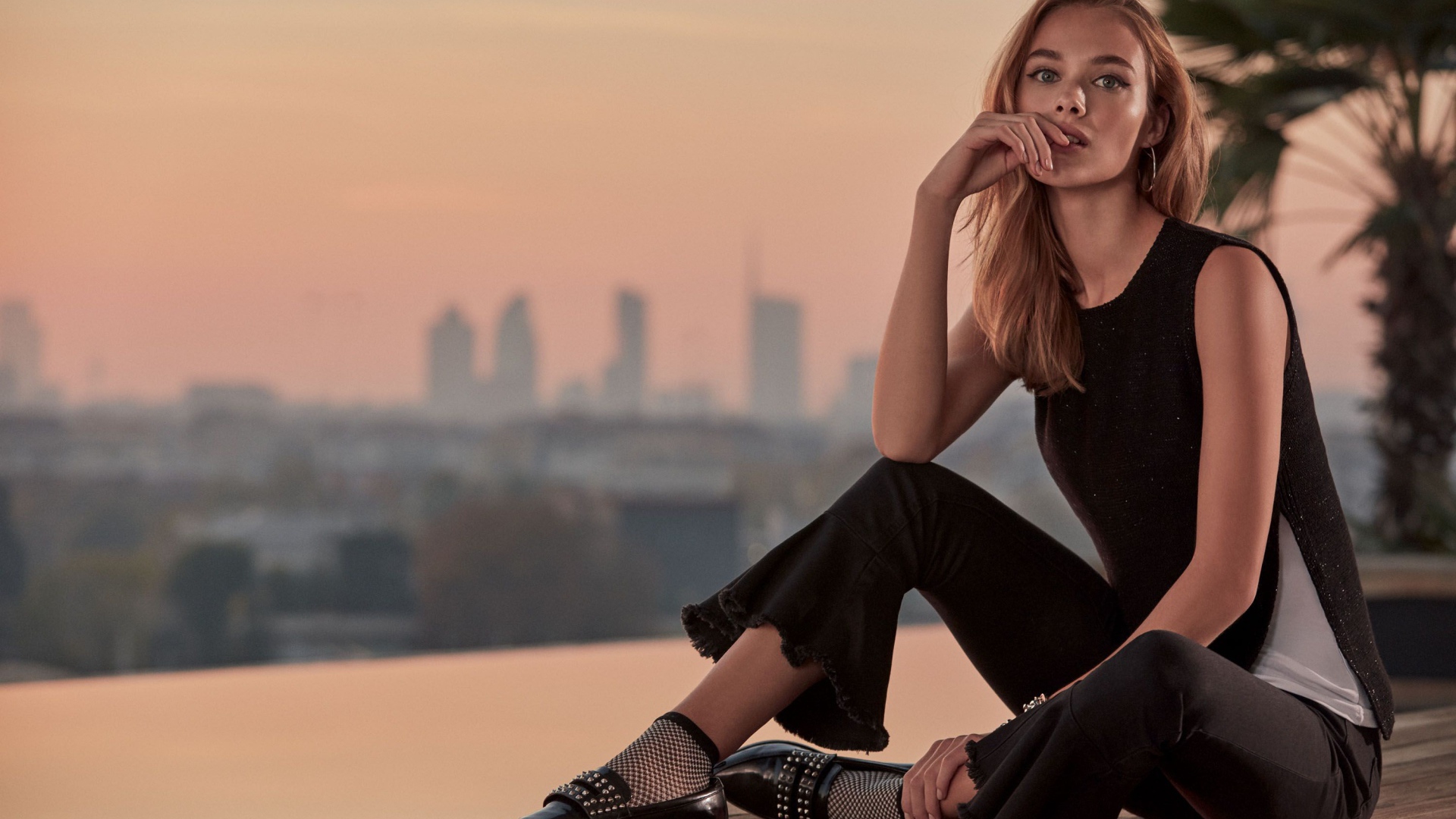 Красивая девушка в черном сидит  на мосту 