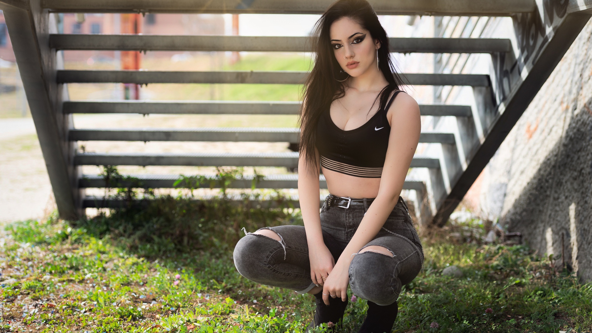 Красивая девушка сидит под лестницей 