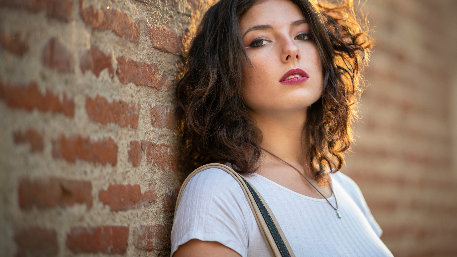 Красивая девушка стоит у стены 